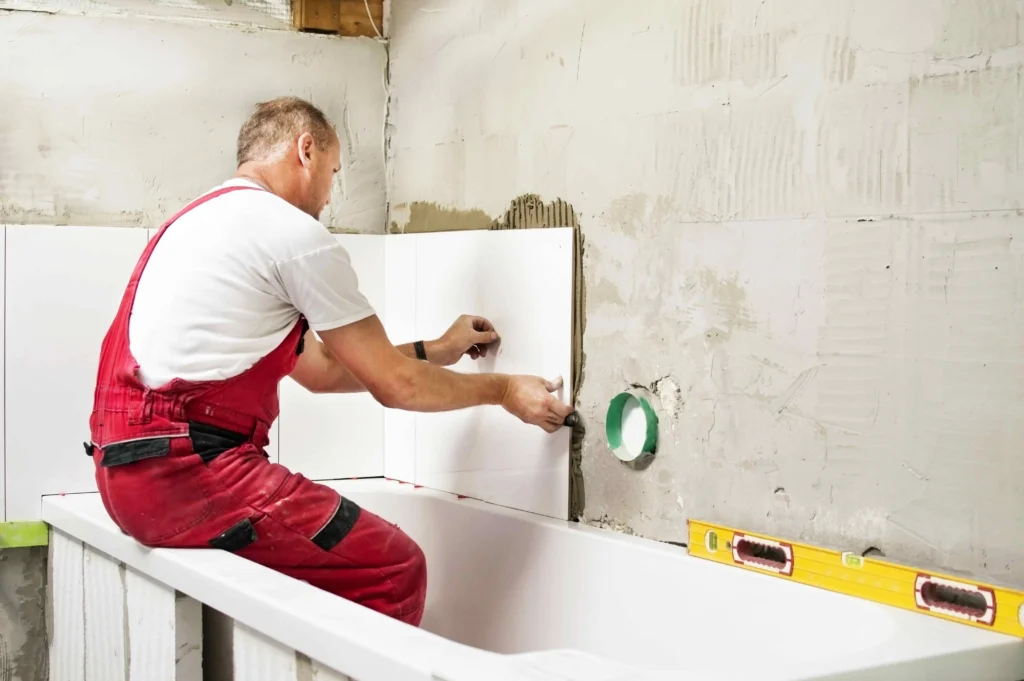 A professional from Builders Cromwell working on bathroom renovation Cromwell, installing tiles with precision.